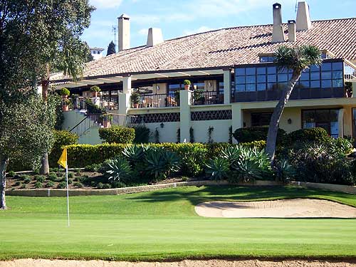 Clubhouse at Rio Real golf with a green, bunker and pin in the foreground.