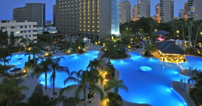The Sol Principe hotel swimming pool at night lit up and viewed from the air.
