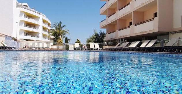 Swimming pool at the Invisa Hotel La Cala Ibiza with empty cream sunbeds around it.