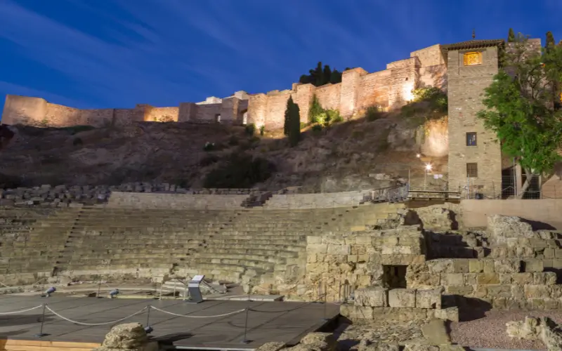 El Teatro Roman at night with the Alcazaba in the background.